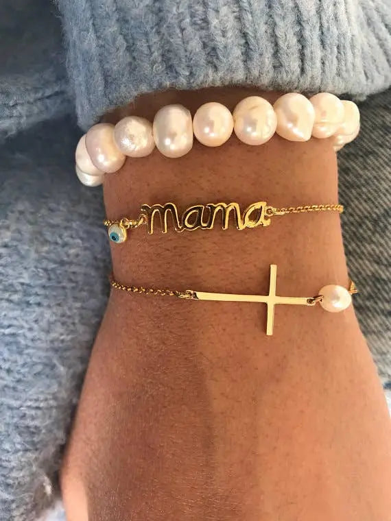 Pulsera cruz Horizontal porté sur main con d'autres bracelets
