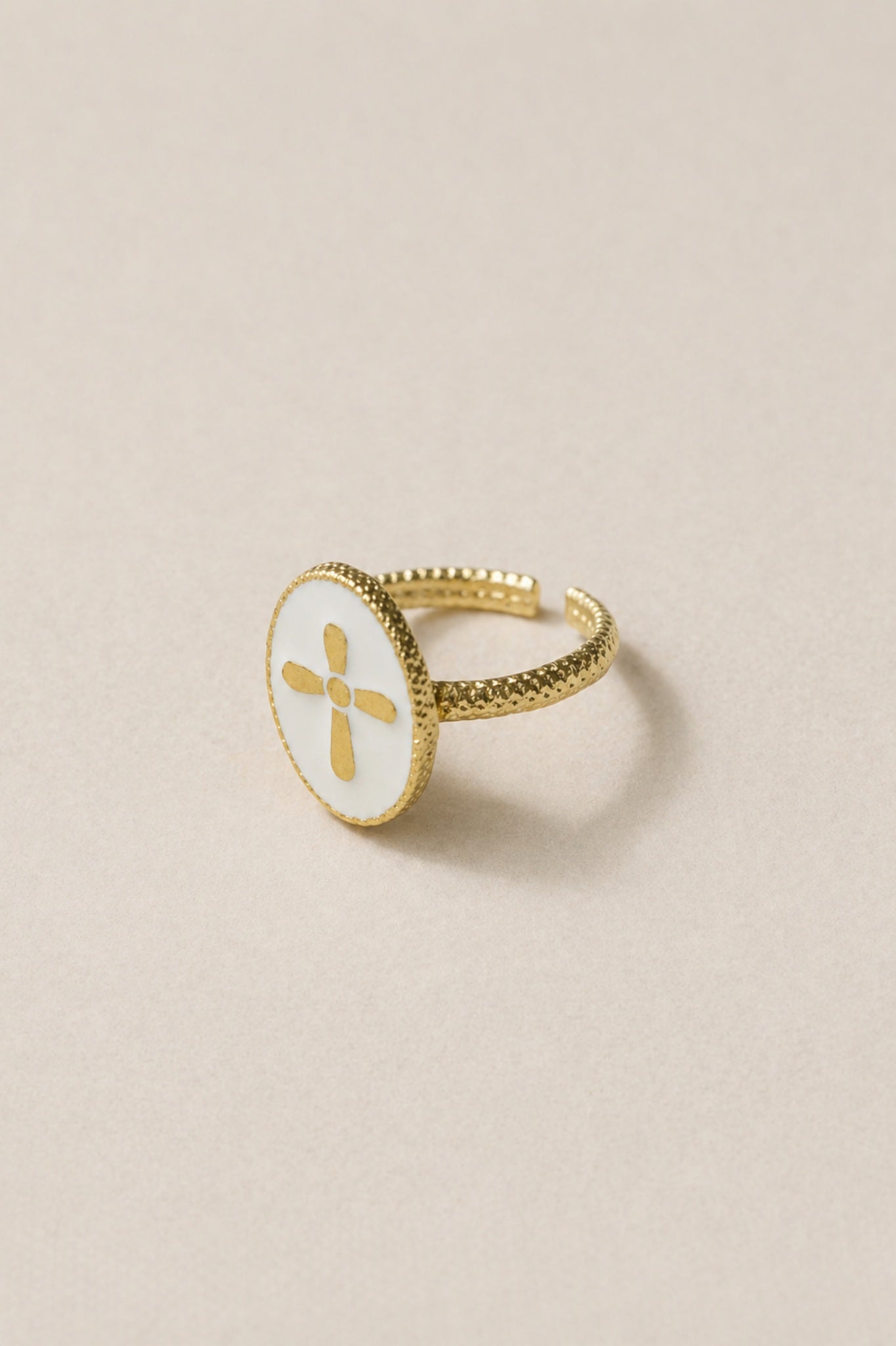 Bague Croix Nacrée photographiée seule sur fond beige rosé épuré