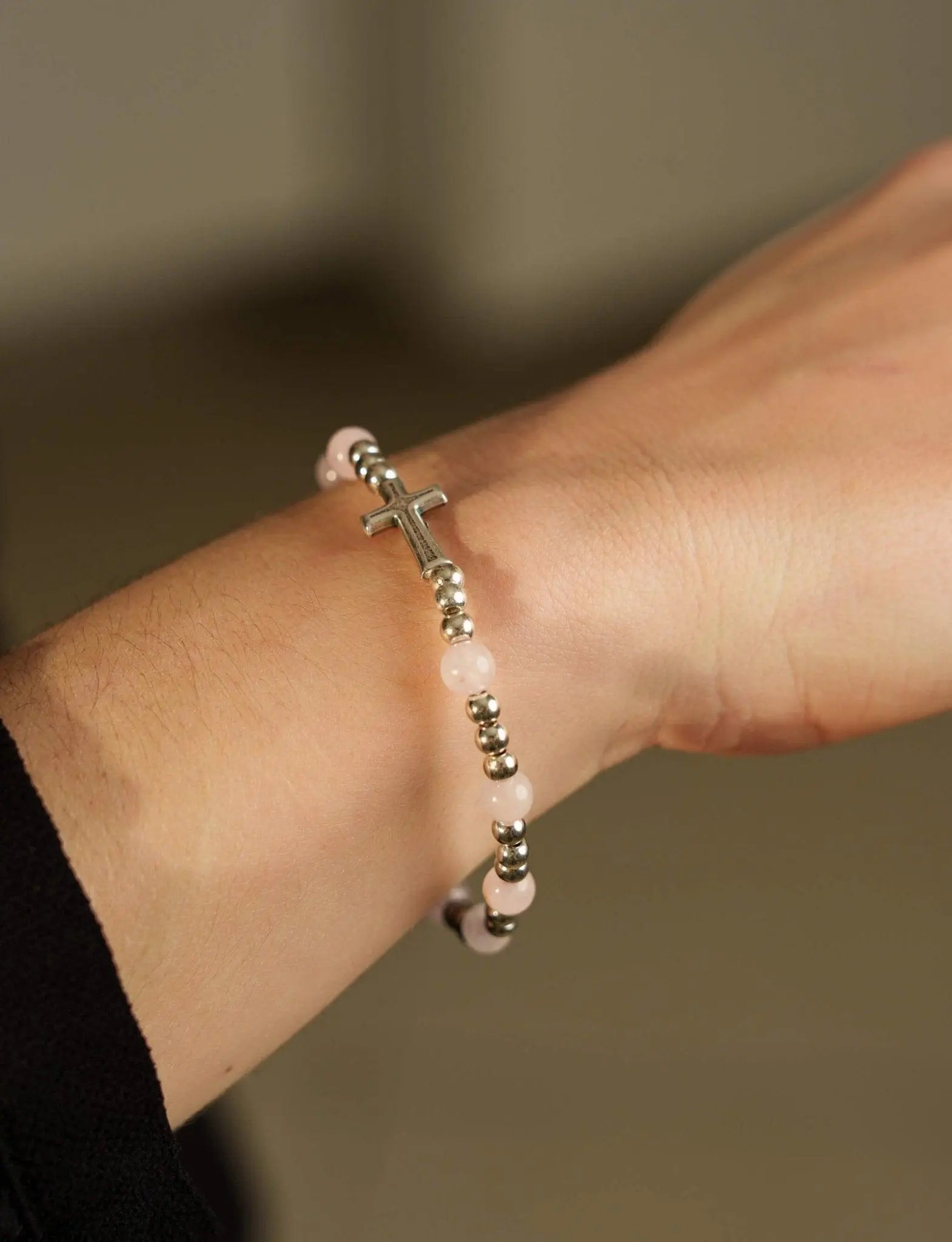 Bracelet dizainier en quartz rose porté avec symbole chrétien