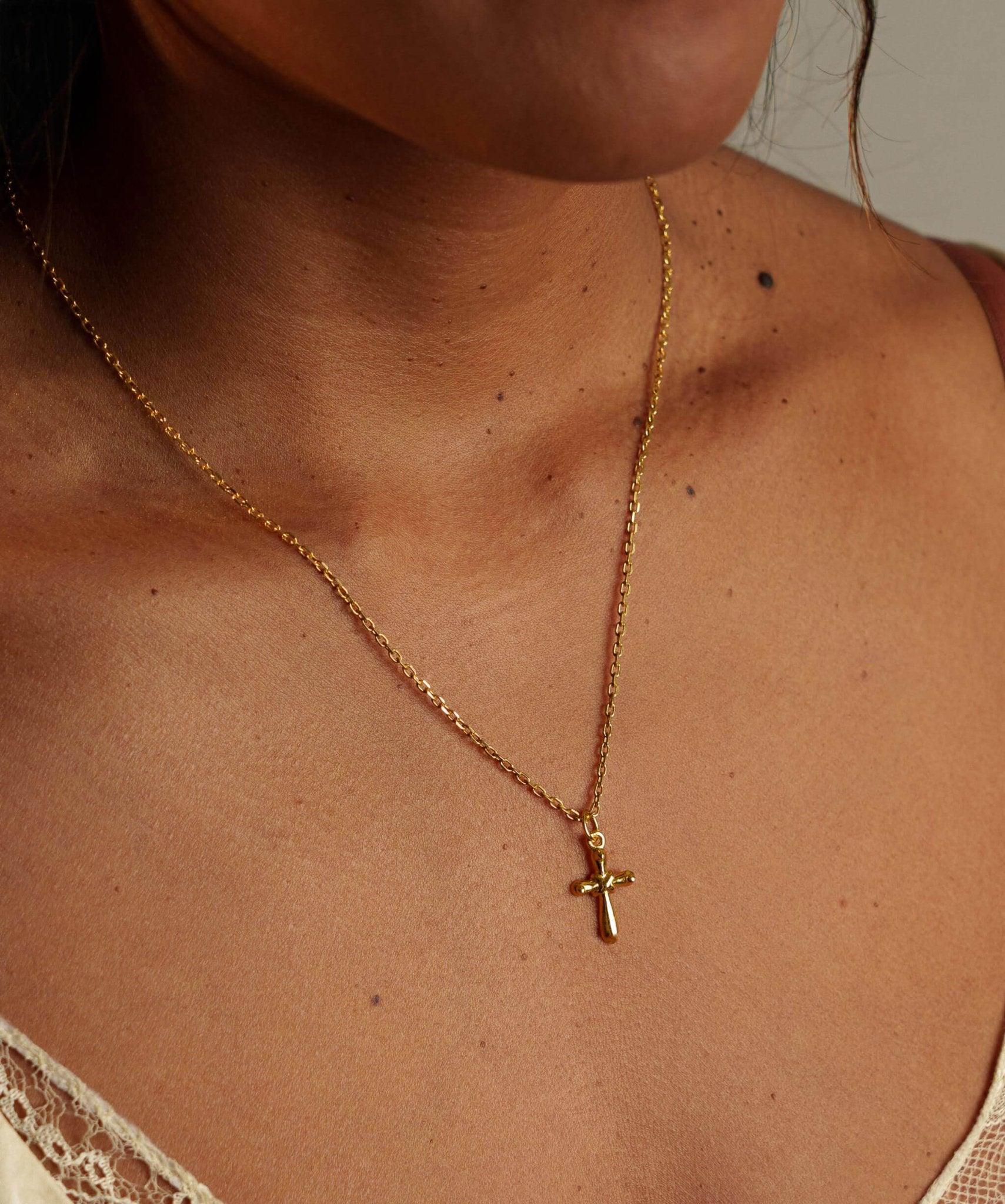 Collier Croix Déborah en plaqué or porté au cou par une femme 
